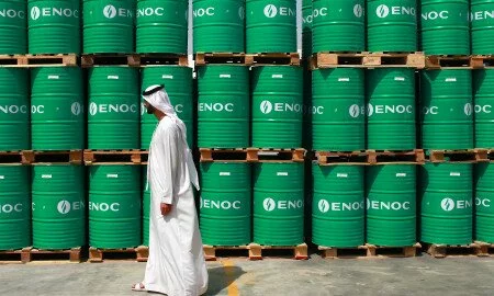 A visitor passes ENOC-branded oil barrels stored at the Emirates National Oil Co. lubricants and grease manufacturing plant in Fujairah, United Arab Emirates, on Monday, March 12, 2012. ENOC, as Dubai's government-owned refiner is known, will expand the plant's capacity to 250,000 tons a year by 2014, it said. Photographer: Gabriela Maj/Bloomberg