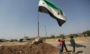 Civilians walk past an opposition flag erected in the northern Syrian rebel-held town of Azaz, in Aleppo Governorate, Syria, October 9, 2016. REUTERS/Khalil Ashawi